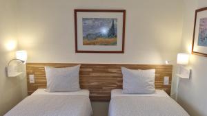 two beds in a room with two lights on the wall at Margarida Guest House - Rooms Lisbon South by Rosado in Almada