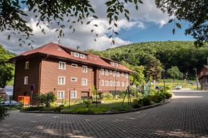 a large wooden building with a hill in the background at Chata pod Ostrým vrchom in Soblahov