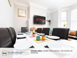 een kamer met een tafel met stoelen en een televisie bij Scarborough Stays - Ashville Lodge - 5 Bedroomed house - Sleeps 9 in Scarborough