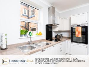 a white kitchen with a sink and a window at Scarborough Stays - Ashville Lodge - 5 Bedroomed house - Sleeps 9 in Scarborough