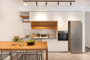a kitchen with white cabinets and a wooden table at HA MESILLA - Modern Collection - By HOMY in Tel Aviv