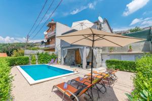 a pool with chairs and an umbrella next to a house at House Lisica in Srinjine