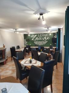 a dining room with tables and chairs and a green wall at Leśne Zacisze in Weremień