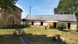 une grange avec une table et des chaises devant elle dans l'établissement Gîte de l'Octroy Poitou, à Oiron