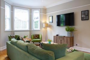 a living room with a green couch and a tv at Lock Keepers Cottage - Detached House in the city in Manchester