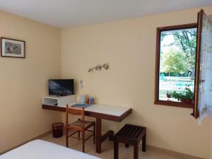 a room with a desk with a television and a window at Hotel du Parc in Thonac