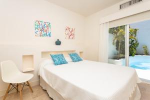 Un dormitorio blanco con una cama y una ventana. en Villa 10.3, en Corralejo