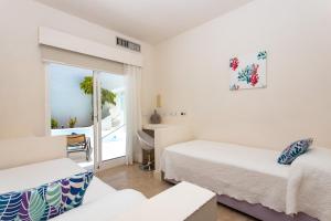 Habitación con 2 camas, escritorio y ventana. en Villa 10.3, en Corralejo