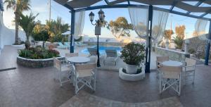 a patio with tables and chairs and a pool at Villa Ilios in Fira