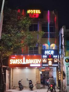 deux motocycles garés devant un bâtiment avec panneaux de néons dans l'établissement Hotel HCB (Hemo Chandra Bhawan), à Brahmapur