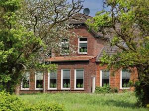 an old brick building with windows in a field at Ferienwohnung Leuchtfeuer - Hof Sinswürden in Butjadingen