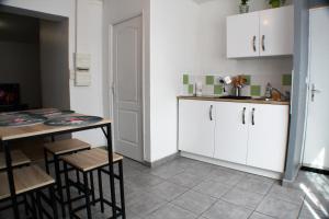 kuchnia z białymi szafkami, stołem i krzesłami w obiekcie Le Cottage des Curie w Calais