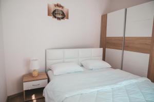 Comfortable apartment in the city center في كاتريني: غرفة نوم بسرير أبيض مع اللوح الأمامي