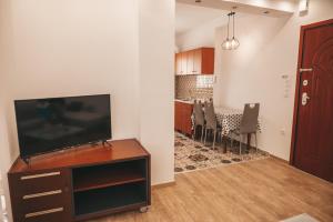 a living room with a tv and a table with chairs at Comfortable apartment in the city center in Katerini
