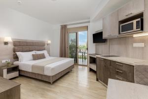a bedroom with a bed and a television and a kitchen at Aria Garden Suites in Nikiti +39 photos
