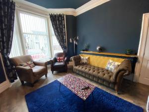 a living room with a couch and a blue wall at Blackpool Abode - The Cinema House in Blackpool