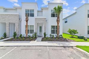 a white house with palm trees in front of it at New Cozy & Spacious Townhouse near Disney - 4BR, 3FB, and Pool in Orlando