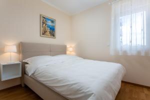 a white bed in a white bedroom with a window at GAJO DELUXE in Trogir