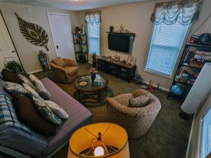 a living room with a couch and chairs and a tv at The Estate Loft in Downtown Milford in Milford