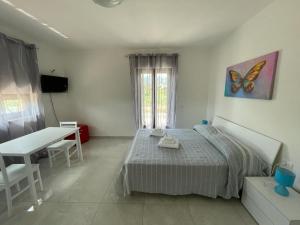 1 dormitorio con cama, mesa y pintura de mariposas en B&B Il Dolce Nido, en Tortora