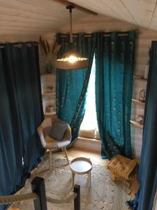 sala de estar con cortinas azules y silla en La Tiny Breizh, en La Poëtevinière