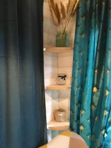 1 dormitorio con cortina azul y estanterías con plantas en La Tiny Breizh, en La Poëtevinière