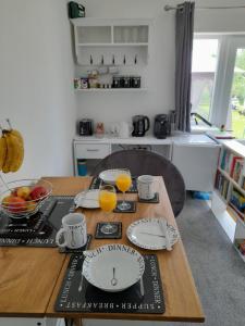 a kitchen table with plates and cups and orange juice at Nar river b&b in Kings Lynn