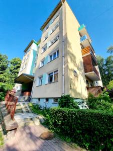 ein hohes weißes Gebäude mit Büschen davor in der Unterkunft Górski Apartament in Karpacz