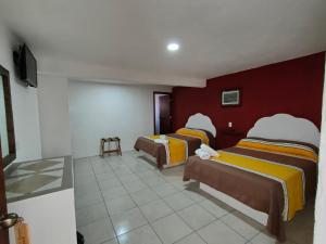 Hotel Hacienda Morales. في غواناخواتو: ثلاثة أسرة في غرفة بجدران حمراء وبيضاء