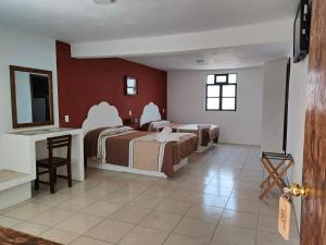 a hotel room with two beds and a desk at Hotel Hacienda Morales. in Guanajuato