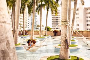 a woman in a hammock in a pool with palm trees at Four Seasons Hotel Miami in Miami