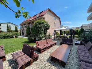 a backyard with a wooden table and chairs and a house at Ametist Casa Leului in Mamaia Sat/Năvodari