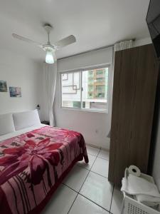 1 dormitorio con cama roja y ventana en Residencial Dubai Centro, en Balneário Camboriú