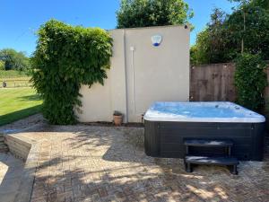 una bañera de hidromasaje en un patio junto a una valla en Large Country House - Hot Tub - Pool Table - BBQ - 5 Bedrooms - Log Burner, en Three Legged Cross