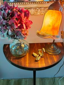 una mesa con una lámpara y un jarrón de flores en chambres d'hotes " Le Magnolia ", en Sainte-Croix-aux-Mines