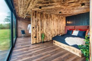 - une chambre avec un lit et un mur en bois dans l'établissement Rusty Boathouse, à Llanarth