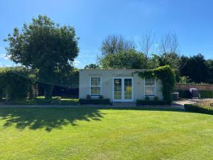 una pequeña casa blanca con un gran patio en Large Country House - Hot Tub - Pool Table - BBQ - 5 Bedrooms - Log Burner, en Three Legged Cross