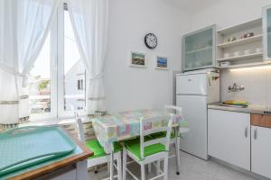 a kitchen with a table and chairs and a refrigerator at Apartment Luiza with Terrace in Baška