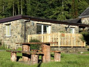 una panchina di legno di fronte a una casa in pietra di Abergwynant Farm Glamping & Apartments a Dolgellau