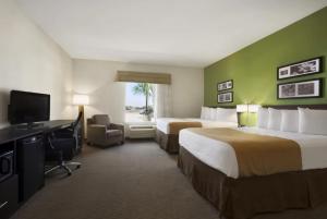 ein Hotelzimmer mit 2 Betten, einem Schreibtisch und einem TV in der Unterkunft PetroStay Inn & Suites Cotulla in Cotulla