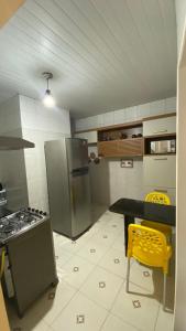 uma cozinha com um frigorífico, uma mesa e cadeiras amarelas em Manancial Flats em Maragogi