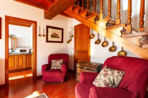 una sala de estar con 2 sillas rojas y una escalera en Casa Enrique en el oriente de Asturias, en Quintana de Llanes