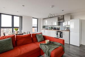 a living room with a red couch and a kitchen at Stunning 2 bed apt with free parking close to CC in Manchester