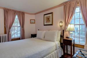 a bedroom with a white bed and two windows at Melville House Newport in Newport