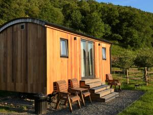 a cabin with chairs and a table and a bench at Abergwynant Farm Glamping & Apartments in Dolgellau