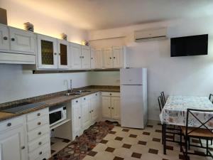 Una cocina con gabinetes blancos y un refrigerador blanco. en Villa Martina, en Isquia
