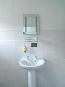 a white bathroom with a sink and a mirror at Howarth House in Lytham St Annes