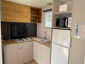 uma pequena cozinha com frigorífico e micro-ondas em Mobilhome tout confort M9 domaine de Lanniron em Quimper