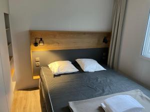 um quarto com uma cama com duas almofadas em Mobilhome tout confort M9 domaine de Lanniron em Quimper