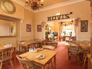 a restaurant with wooden tables and chairs and a clock at Howarth House in Lytham St Annes